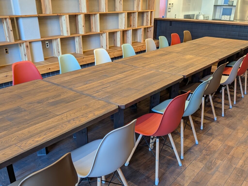 たかまつトコトコの長い木製テーブルとカラフルな椅子