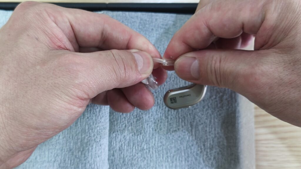 チューブを持って補聴器本体からイヤモールドを外す様子