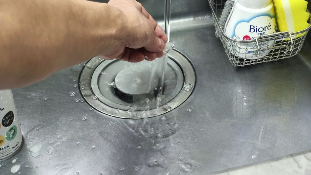 流水でイヤモールドの洗剤をすすぐ様子